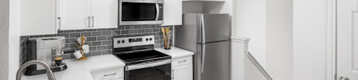 A modern kitchen with stainless steel appliances and white cabinetry.
