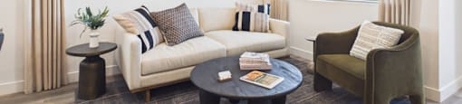 A living room with a white couch, a green armchair, and a coffee table.