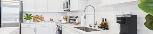 A modern kitchen with white cabinets and stainless steel appliances.