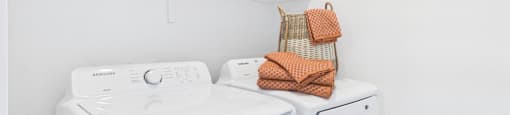 A white washing machine and dryer with a basket on top.