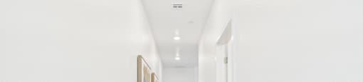 A long hallway with wood floors and white walls.