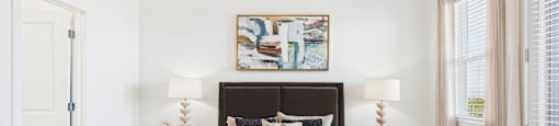 A bedroom with a large bed and a painting on the wall.