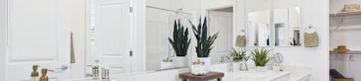 A white bathroom with a double sink and a mirror.