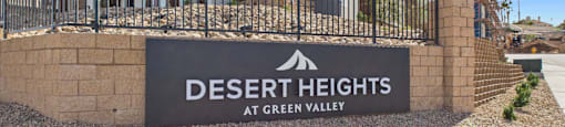 A sign that says "Desert Heights at Green Valley" in front of a building.