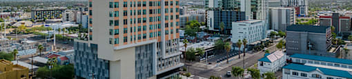 A tall building with many windows is in the foreground of a cityscape.