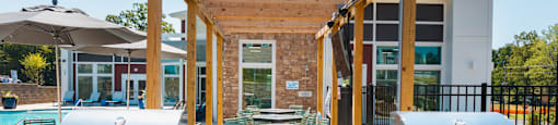 two bbq grills with umbrellas and a pool in the background