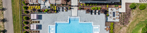 A large swimming pool surrounded by a grassy area and trees.