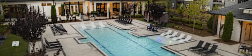 a swimming pool with lounge chairs in front of a house