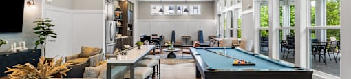 A pool table is in the middle of a room with a bar and a TV.