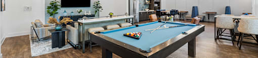 A pool table is in the middle of a room with a TV and a bar.