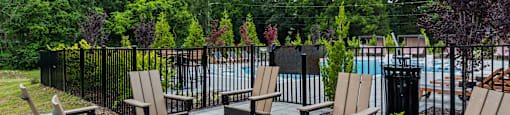 A patio with chairs and a table with a pool in the background.
