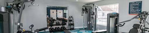 a gym with weights and other exercise equipment in a room with a window