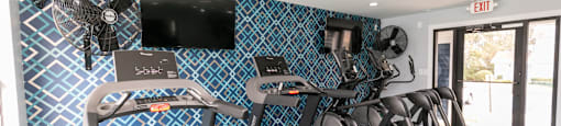 a gym with treadmills and a tv on the wall