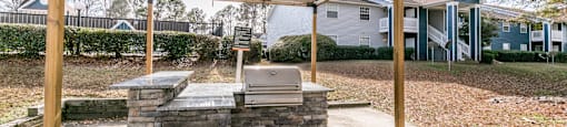 a covered patio with a grill and a stone wall