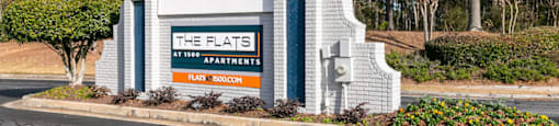 a sign for the flats hotel apartments on the side of a road