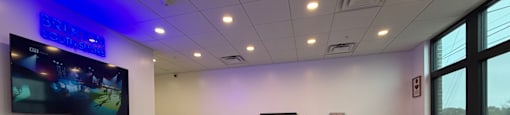 A ping pong table is in the middle of a room with a TV on the wall.