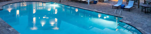 a swimming pool with lounge chairs and a building in the background
