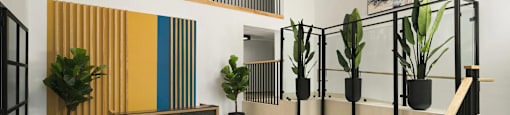 A modern office lobby with a staircase, chairs, and a television.