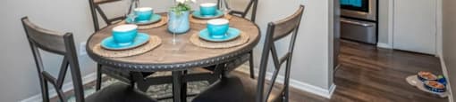 a dining area with a table and chairs and a kitchen in the background