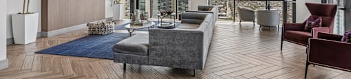 A modern living room with a large grey sofa and a wooden floor.