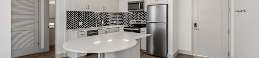 A modern kitchen with a wooden floor and white walls.