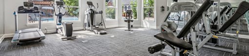 A spacious gym with a variety of equipment including treadmills, elliptical machines, and weight machines.