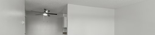 an empty living room with wood flooring and a ceiling fan