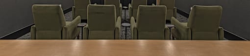 A conference room with a long table and chairs facing a screen.