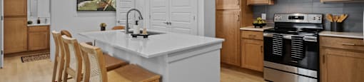 A kitchen with a white countertop and wooden chairs.