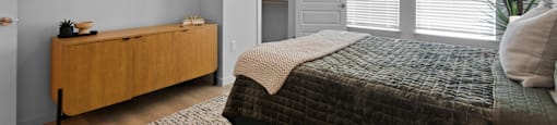 A bedroom with a bed, dresser, and window with blinds.