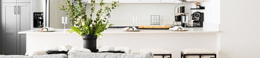A grey couch with a black pillow and a vase with flowers on a coffee table.