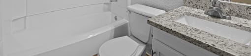 A white bathroom with a toilet, sink, and bathtub.