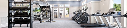a gym with cardio equipment and weights on the floor