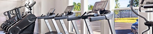 a gym with cardio equipment and large windows