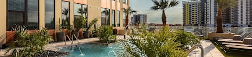 A pool with a waterfall in front of a building with a balcony.