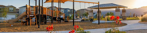 A playground with a slide and a canopy structure is surrounded by houses.