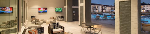 A modern living room with a large window overlooking a pool and buildings.