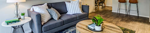 A living room with a grey couch, a wooden coffee table, and two abstract art pieces on the wall.