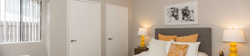 A bedroom with a large bed, two nightstands with lamps, and a window with blinds.