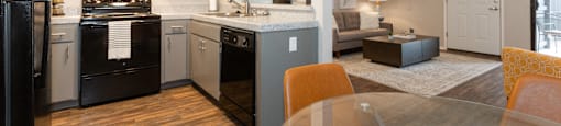 A modern kitchen with a black refrigerator and wooden floors.