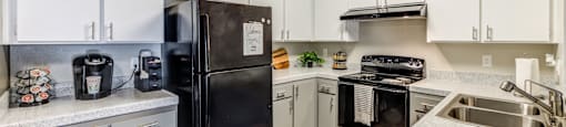 A kitchen with a black refrigerator and white cabinets.
