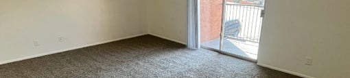an empty living room with a door to a balcony