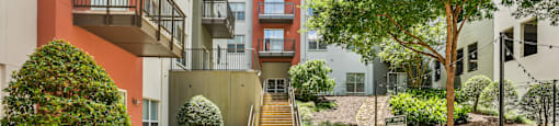 A pathway leads up a set of stairs in a landscaped courtyard.