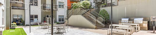 A patio area with a table and chairs is surrounded by apartment buildings.