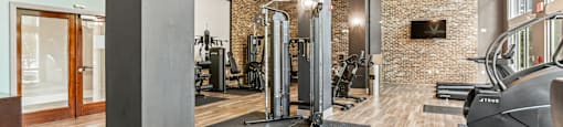 A gym with a variety of equipment and a brick wall.