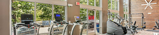 A gym with treadmills and a wooden floor.