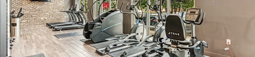 A gym with a brick wall and a row of exercise bikes.