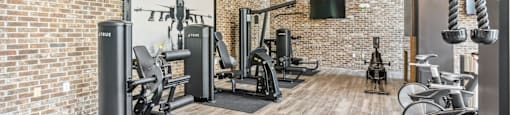 A gym with a brick wall and wooden floors.