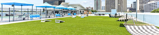 A large grassy area with a fence and a few umbrellas.