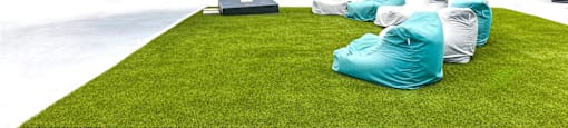 A white building with a black roof and a white awning with a green lawn in front.